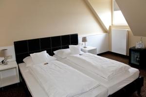 a large white bed with white sheets and pillows at Schnellenburg in Düsseldorf