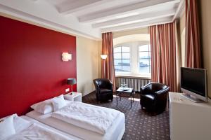 a hotel room with a bed and two chairs and a television at Schnellenburg in Düsseldorf