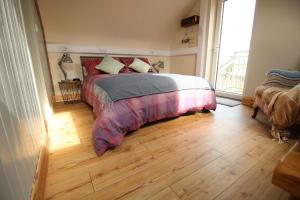 um quarto com uma cama e piso em madeira em McHugh's Loft em Rathmullan