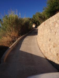 un camino con una pared de piedra junto a una acera en Casa Rossa del Cappero Sottano en Lipari