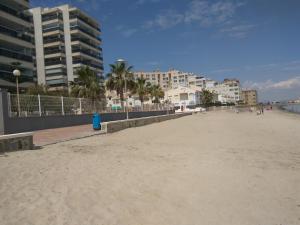 a sandy beach with buildings and palm trees and buildings at Apartamento en residencial viña del mar in La Manga del Mar Menor