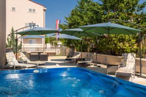a pool with chairs and umbrellas on a patio at Hotel Abalone in Crikvenica