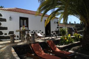 a house with two chairs and a palm tree at Casa Rural Los Geranios 1 in Tijarafe
