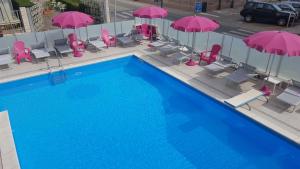 einen Blick über einen Pool mit rosa Sonnenschirmen und Stühlen in der Unterkunft Hotel Mont Blanc in Bellaria-Igea Marina