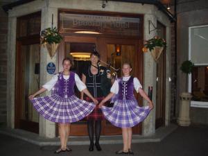 a group of three women in tartan kilts outside a building at Beaufort Hotel in Inverness