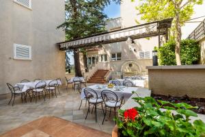 a patio with white tables and chairs on a patio at Hotel Abalone in Crikvenica