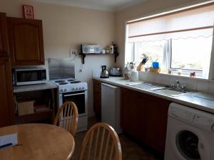 a kitchen with a sink and a stove and a table at 39 Gravir, Isle of Lewis in Graver