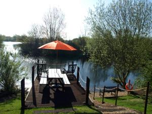 a table and chairs with an umbrella on a dock at Lakeview at Lodge Farm in Norwich