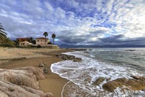 una playa con rocas, una casa y el océano en T2 Terrasse Vue Mer - Route des Sanguinaires, en Ajaccio