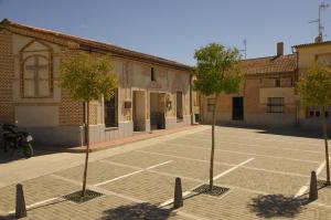 dos árboles en un estacionamiento frente a un edificio en Casa Rural "Hazanas" Adanero, en Adanero