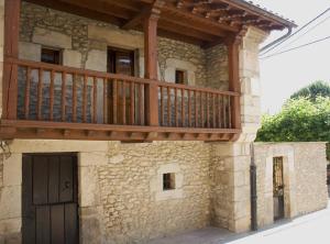 a house with a wooden balcony on the side of it at La Carriella in Colombres