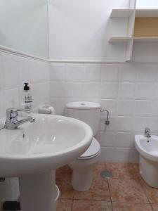 a white bathroom with a sink and a toilet at La Carriella in Colombres