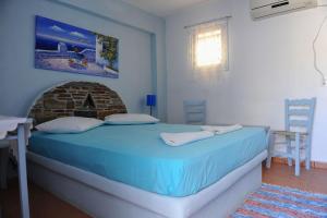 a bedroom with a blue bed and a fireplace at kamares kythnos in Kanala