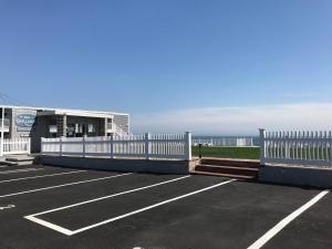 a parking lot with a white fence next to the ocean at The Garlands Motel in Dennis Port