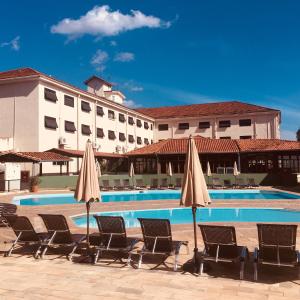 a pool with chairs and umbrellas in front of a hotel at Guararema Parque Hotel in Guararema