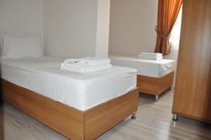two beds in a room with white sheets and towels at İskele Otel in Tasucu