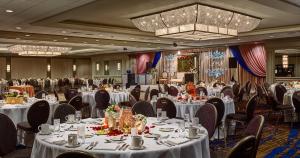 a banquet hall with white tables and chairs and a chandelier at The Hotel at Auburn University in Auburn