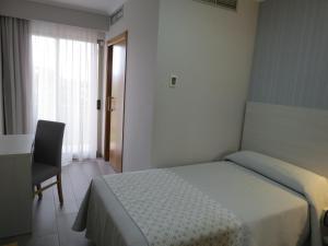 1 dormitorio con 1 cama, 1 silla y 1 ventana en Hotel La Lanzada en A Lanzada