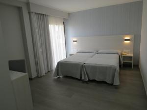 a hotel room with a bed and two lamps at Hotel La Lanzada in A Lanzada