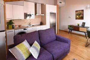 a living room with a purple couch and a kitchen at Arbesa Huesca in Huesca