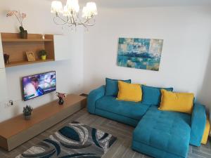 a living room with a blue couch and a tv at Holiday Apartment Mamaia Nord in Mamaia Nord