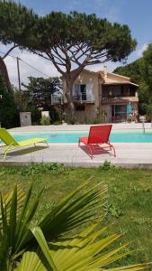 uma cadeira vermelha em frente a uma casa com piscina em Boost Your Immo La Courtaude T3 N em Six-Fours-les-Plages