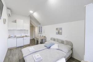 a white bedroom with a bed and a kitchen at Anita's Studio Apartments in Ljubljana