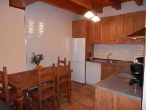 cocina con mesa de madera, sillas y fregadero en Casa Rural El Dolmen, en Bernúy-Salinero