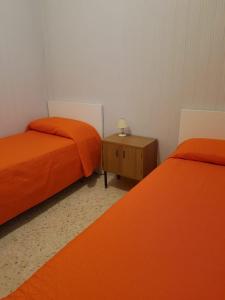 モノーポリにあるVilla Lillyのオレンジのシーツとテーブルが備わる客室のベッド2台