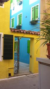 een blauw en geel gebouw met groene luiken bij Casa Fiorella in Caorle