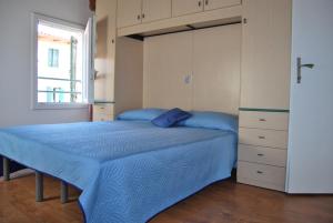 een slaapkamer met een bed met blauwe lakens en een raam bij Casa Fiorella in Caorle
