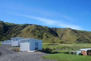 une rangée de bâtiments devant une montagne dans l'établissement Waimeha Camping Village, à Ngawi