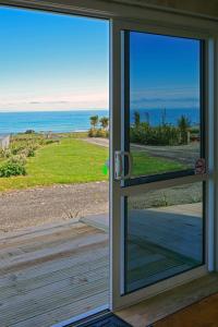 eine Glasschiebetür mit Meerblick in der Unterkunft Waimeha Camping Village in Ngawi