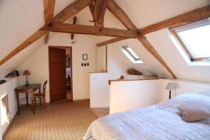 sypialnia na poddaszu z łóżkiem i biurkiem w obiekcie Maison St Mayeul w mieście Bouère