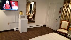 a room with a tv and a bed and a mirror at Stucco Lodge in Bangor