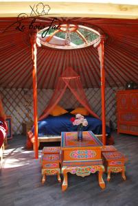 Habitación con cama en una yurta con mesa en Le Bois Faé, en La Bastide