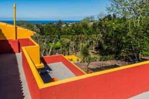 a yellow and red building with a view of the ocean at A Casa Amarela in Capelas