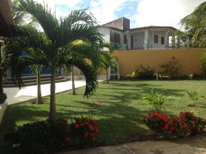 a yard in front of a house with palm trees and flowers at Casa praia Aracaju in Aracaju