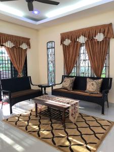 uma sala de estar com sofás, uma mesa e janelas em Family Homestay em Kuala Terengganu