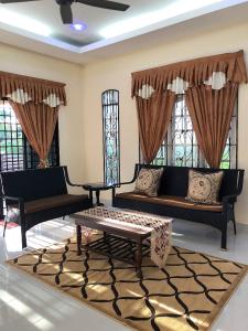 a living room with couches and a table and windows at Family Homestay in Kuala Terengganu