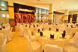 un salón de banquetes con mesas blancas y sillas blancas en ASTON Ketapang City Hotel, en Ketapang