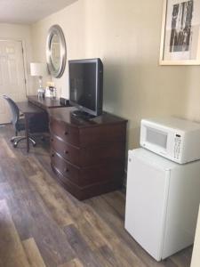 a room with a desk with a microwave and a television at Royal Inn in Sparta