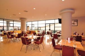 a restaurant with tables and chairs and windows at Aston Ketapang City Hotel in Ketapang