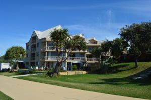 a large apartment building with a palm tree in front of it at Sanctuary Beach Resort in Gold Coast