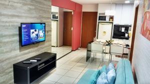 uma sala de estar com um sofá e uma televisão em Apartamento Praia Jatiúca em Maceió