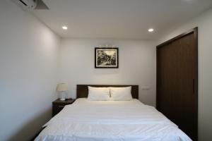 a bedroom with a white bed with a wooden door at Cat Linh ARL55 Hotel in Hanoi