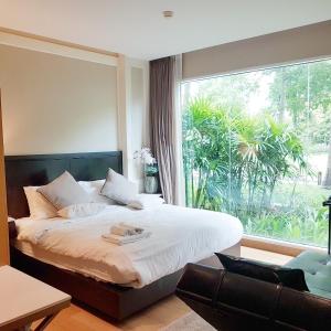 a bedroom with a bed and a large window at Residence Nithiwat Amri Hua Hin in Hua Hin