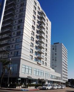 Apartment Peninsula في بونتا دل إستي: مبنى كبير فيه سيارات تقف امامه
