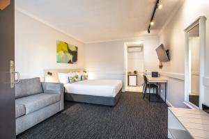 um quarto de hotel com uma cama e um sofá em Nightcap at Matthew Flinders Hotel em Chadstone