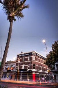 a building with a palm tree next to a street at Haka Lodge Auckland in Auckland